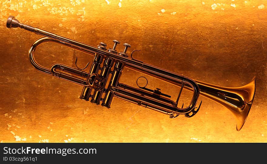 Brass trumpet horn on a golden background. Soft light photograph.