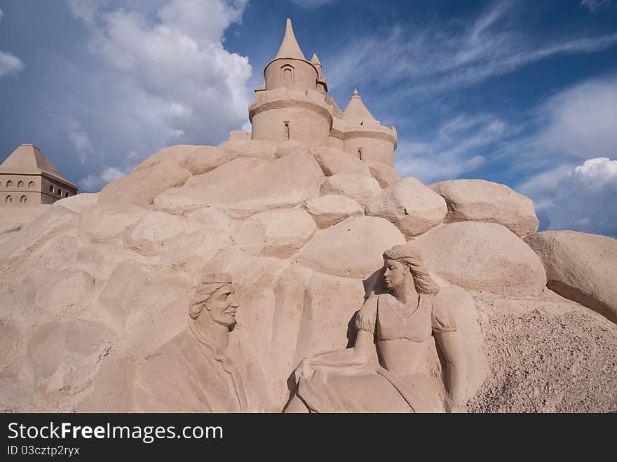 Sand castle and sculpture against blue sky with clouds. Sand castle and sculpture against blue sky with clouds.