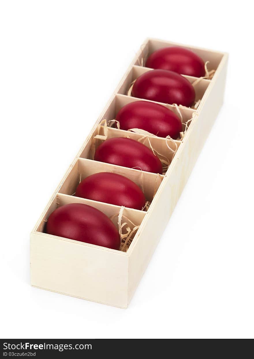 Red eggs in a wooden box on white