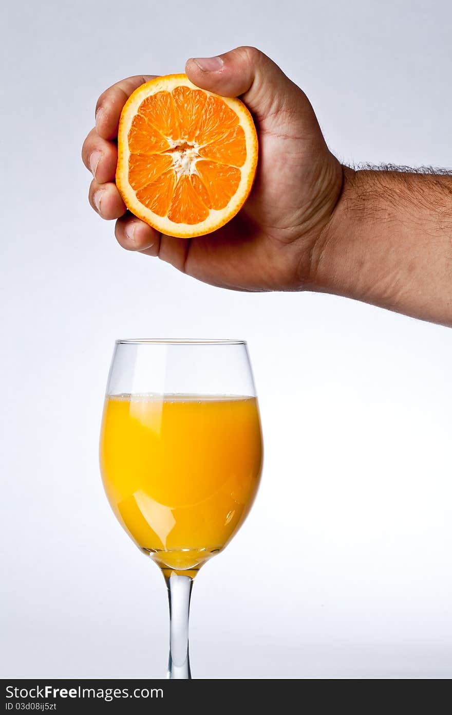 Squeezing orange into a glass of juice. Squeezing orange into a glass of juice