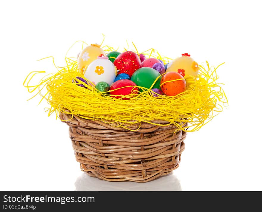 Cheerful easter eggs in straw in a wicker basket isolated over white background. Cheerful easter eggs in straw in a wicker basket isolated over white background