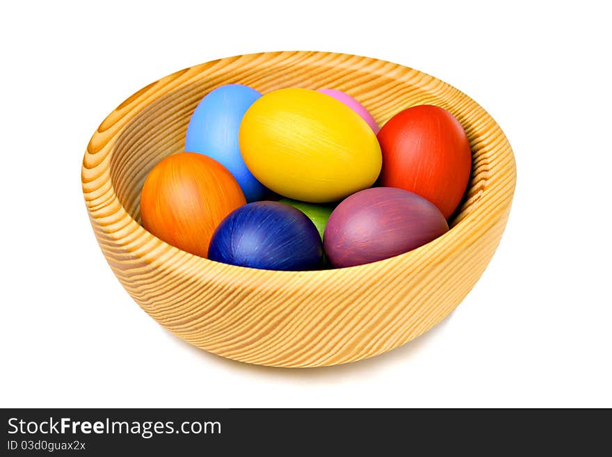 Colorful Easter eggs in wooden bowl, isolated on white