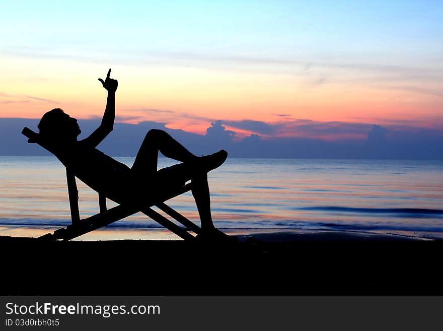 Deckchairs and man on beach at sunset