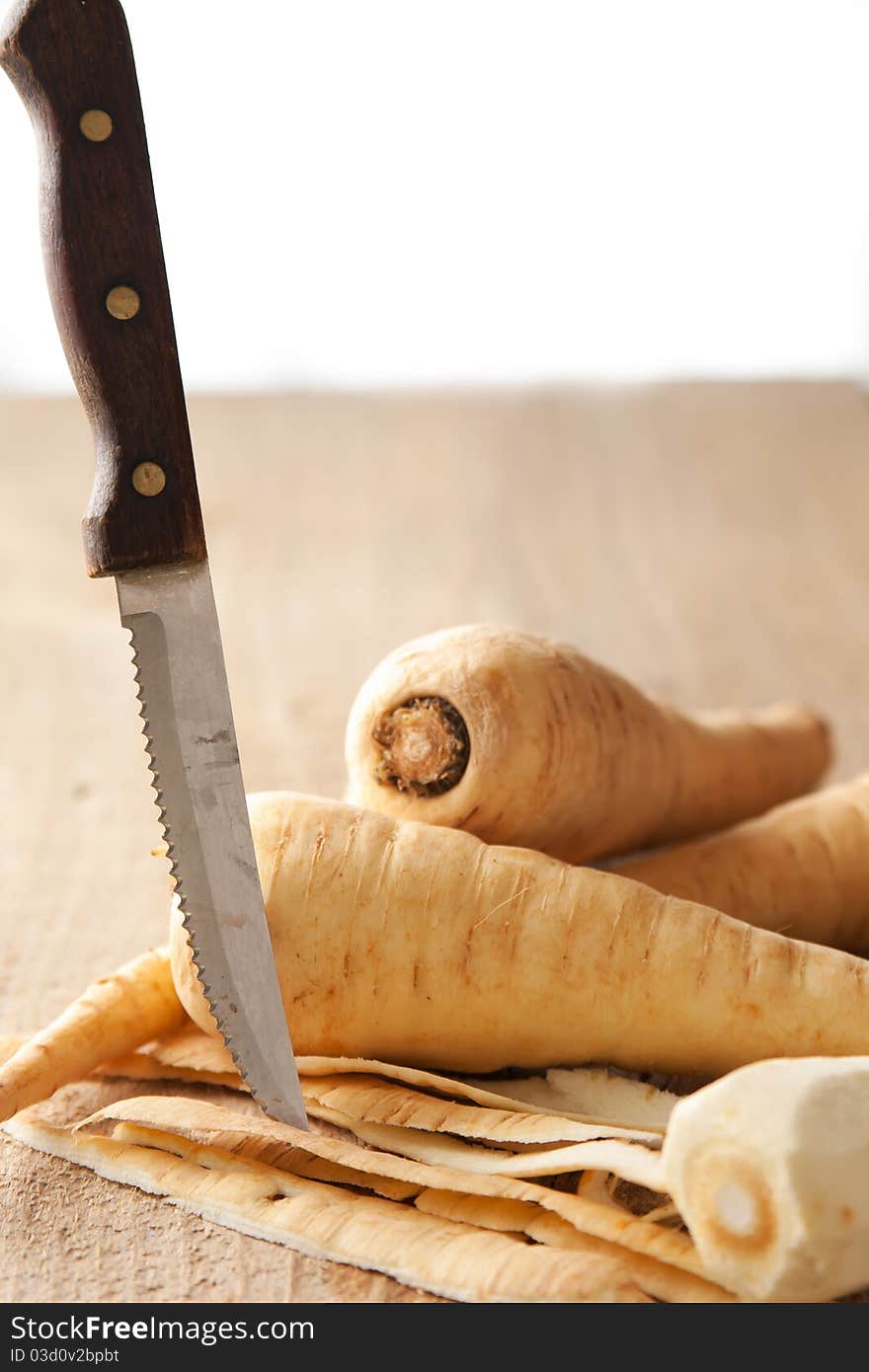 Parsley root, peel and knife on a rustic table