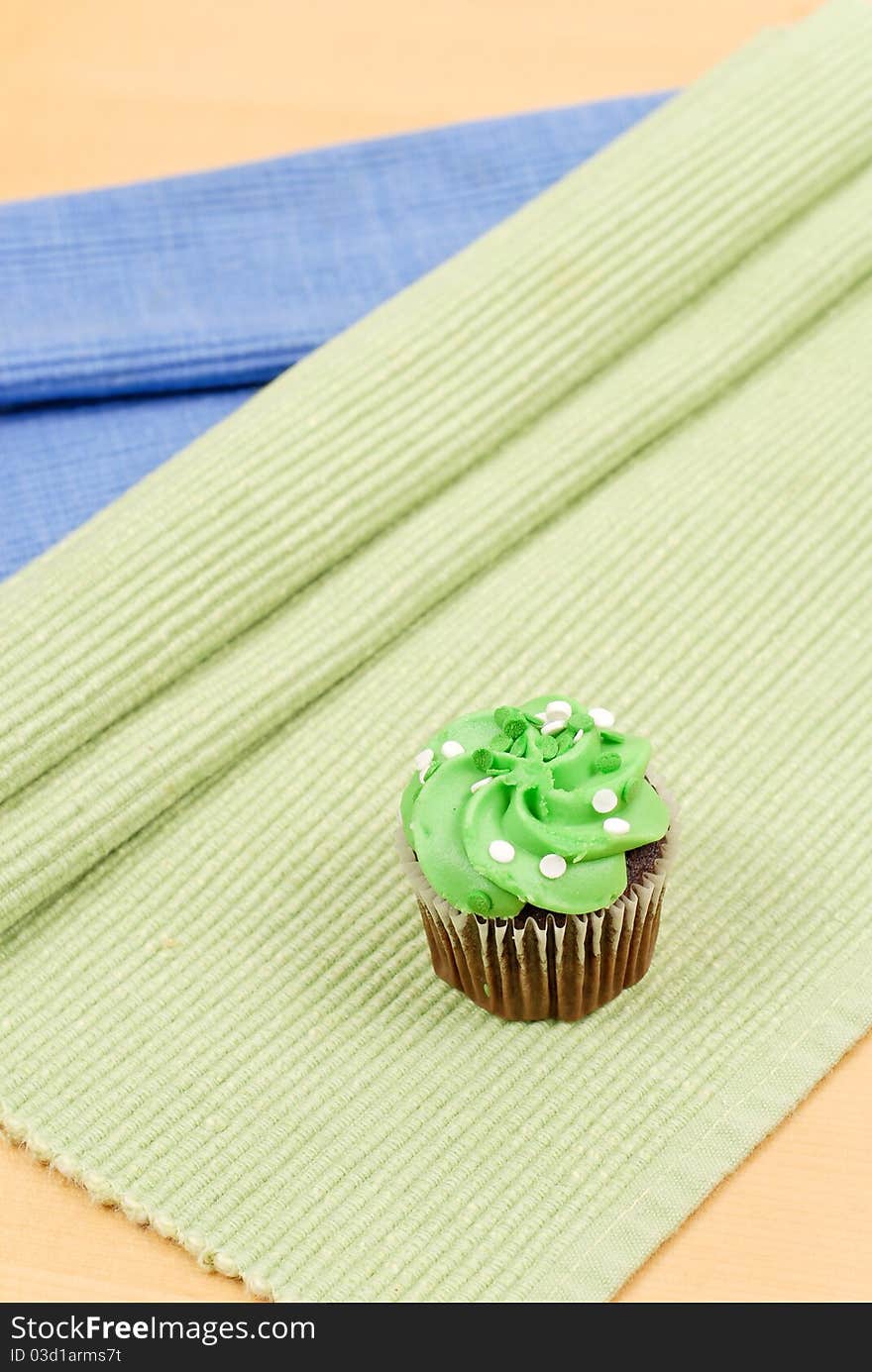 Green Frosting Chocolate Cupcake On Green Mat. Green Frosting Chocolate Cupcake On Green Mat