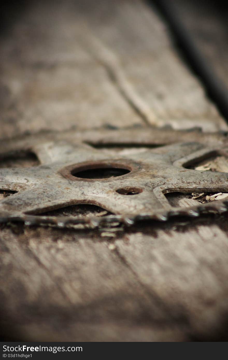 Just a unique view of an old bicycle sprocket laying on an old barn door.