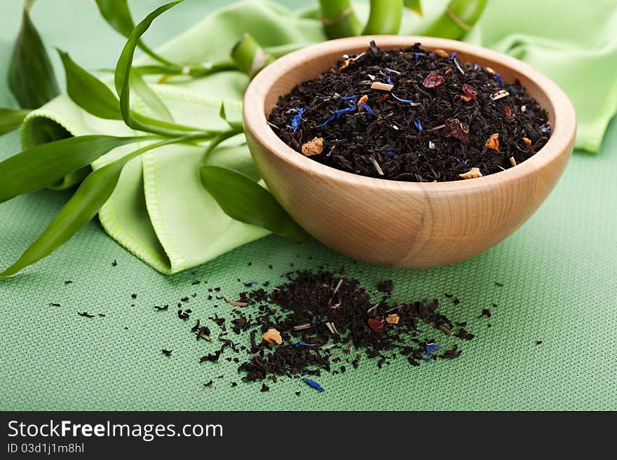 Dry black tea with rose hips and cornflower petals in wooden bowl. Dry black tea with rose hips and cornflower petals in wooden bowl