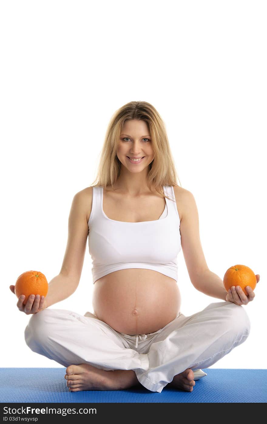 Pregnant woman practicing yoga with oranges isolated on white