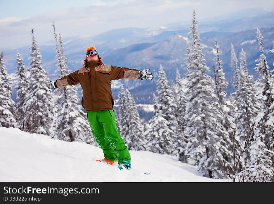 Snowboarder on the mountain with his arms raised