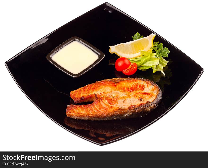 Grilled salmon steak with sauce and lemon isolated