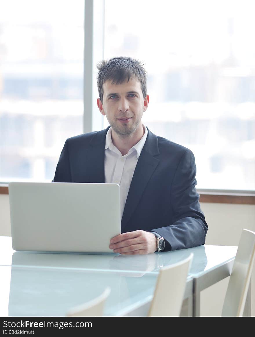 Young business man lawyer with laptop alone in big bright   conference room. Young business man lawyer with laptop alone in big bright   conference room