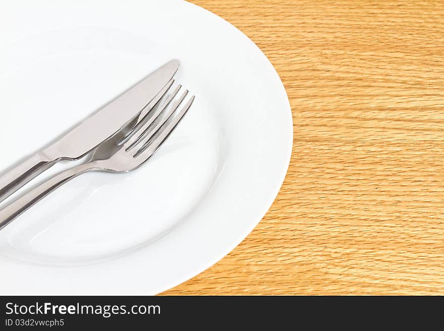 Knife and fork on white plate on table