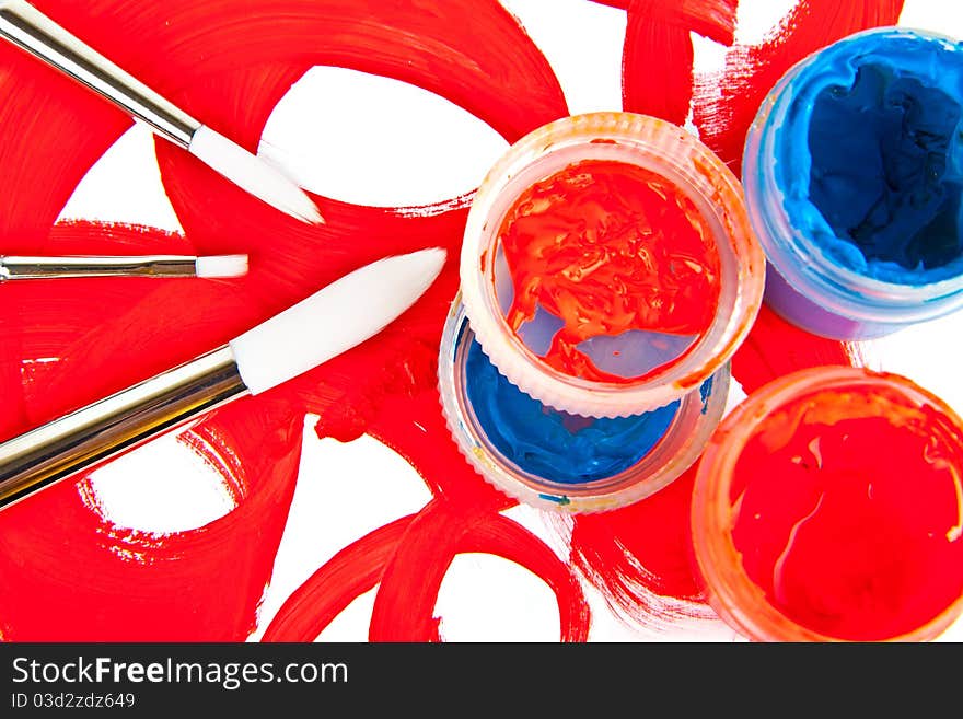 Three brushes and tubes with paint on white