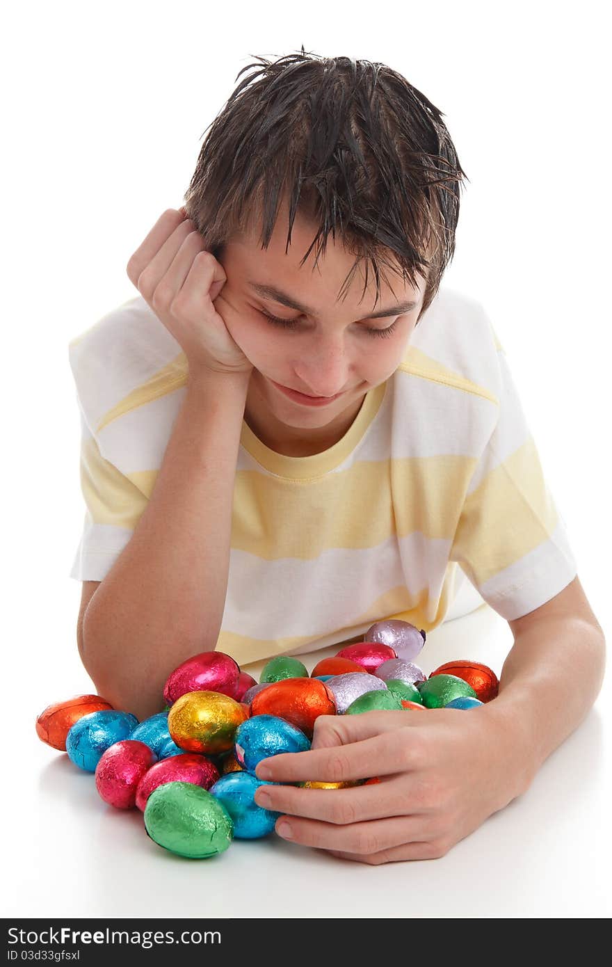 A boy looking down at lots of colourful bright chocolate easter eggs. A boy looking down at lots of colourful bright chocolate easter eggs.