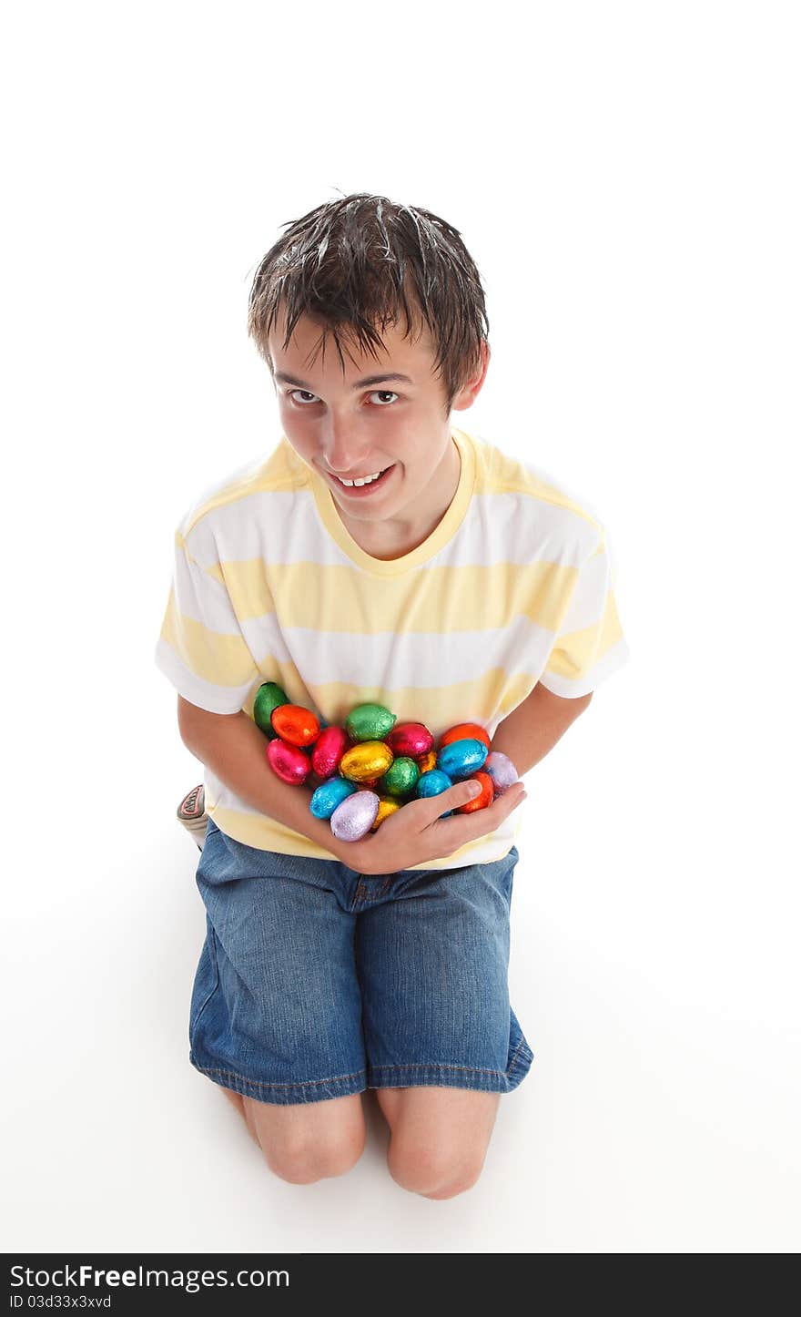 Boy holding an armful of colorful chocolate easter eggs and smiling. White background,. Boy holding an armful of colorful chocolate easter eggs and smiling. White background,