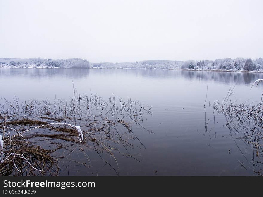 Frozen thawing lake in snow landscape.