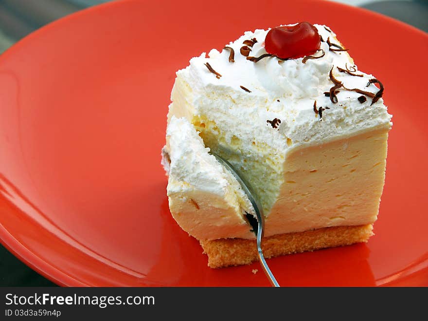 Sweet appetizing creamy cookie on red plate with spoon. Sweet appetizing creamy cookie on red plate with spoon