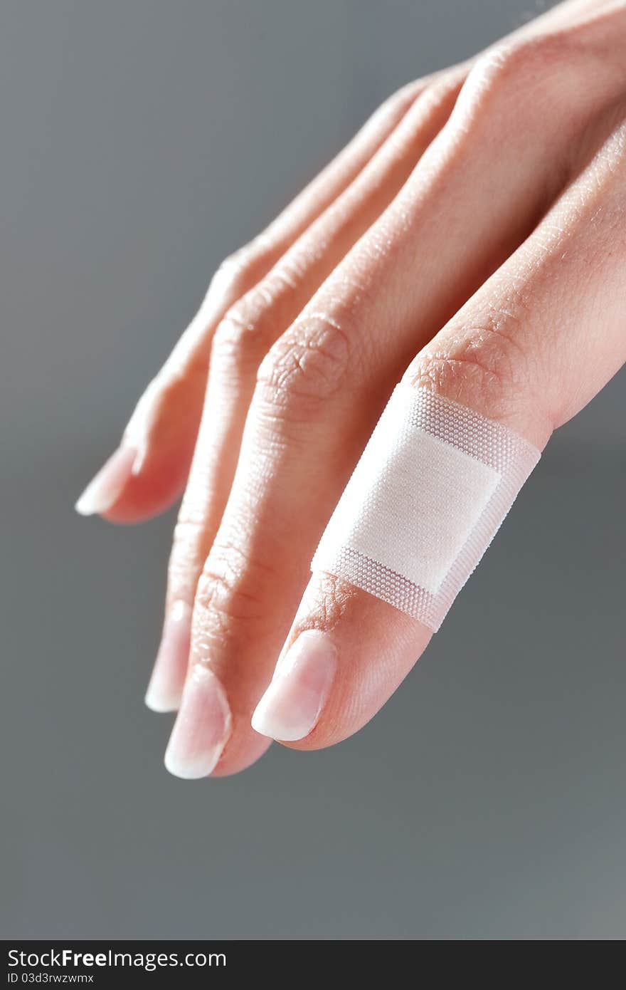 Bandage on female finger, isolated on gray