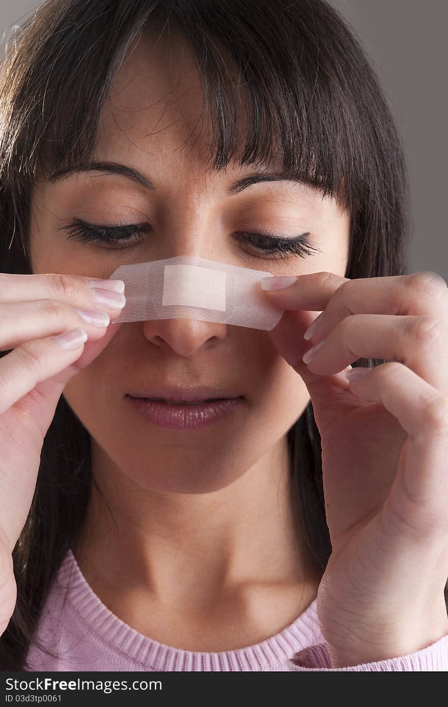 Woman applying bandage on nose