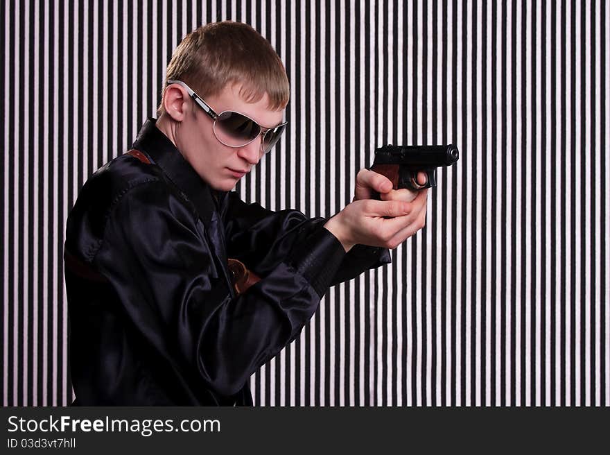 Serious man with a gun standing against striped background