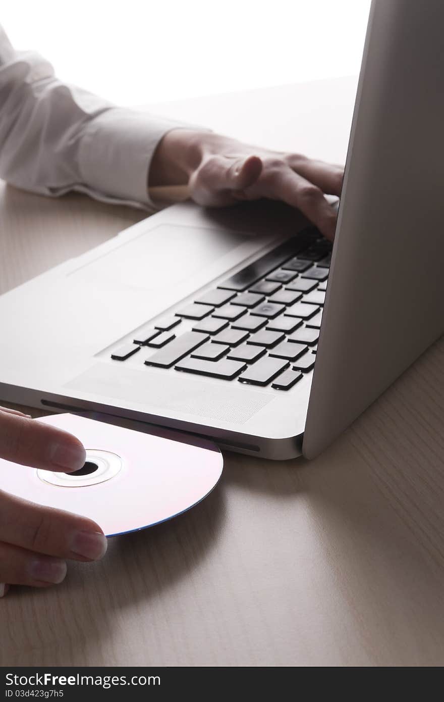 Female Hand placing dvd into laptop