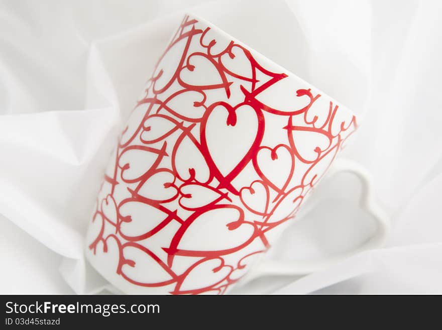 Close up , on a white background, of a cup with stylized hearts printed on it. Close up , on a white background, of a cup with stylized hearts printed on it