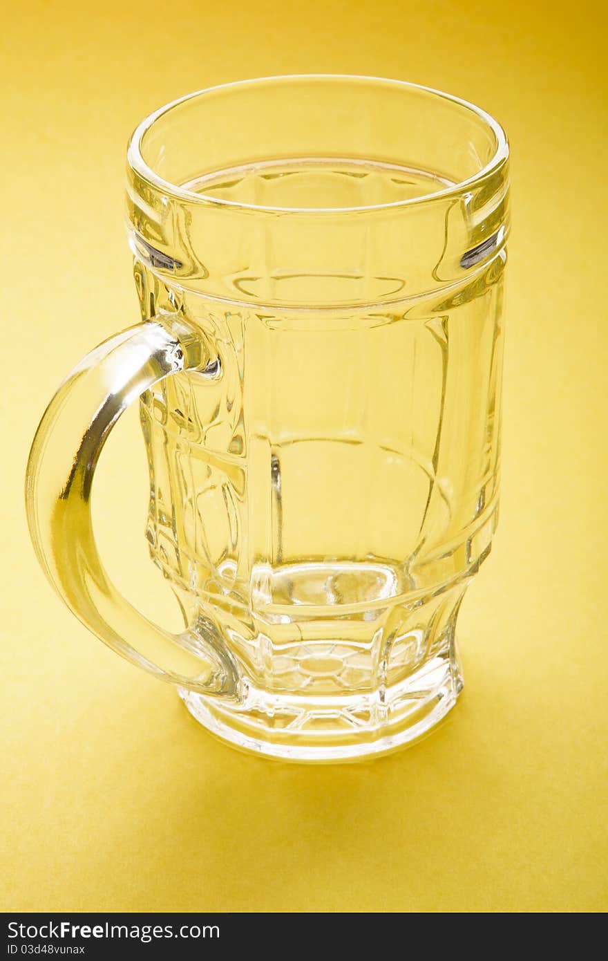 Empty beer mug on a yellow background