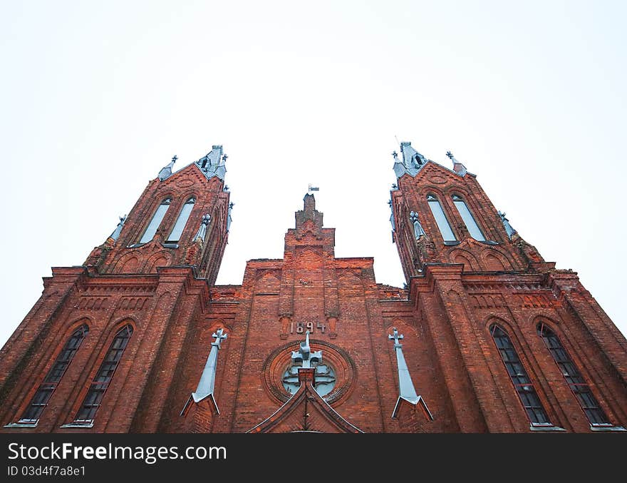 Ancient Catholic cathedral of red brick on sky background