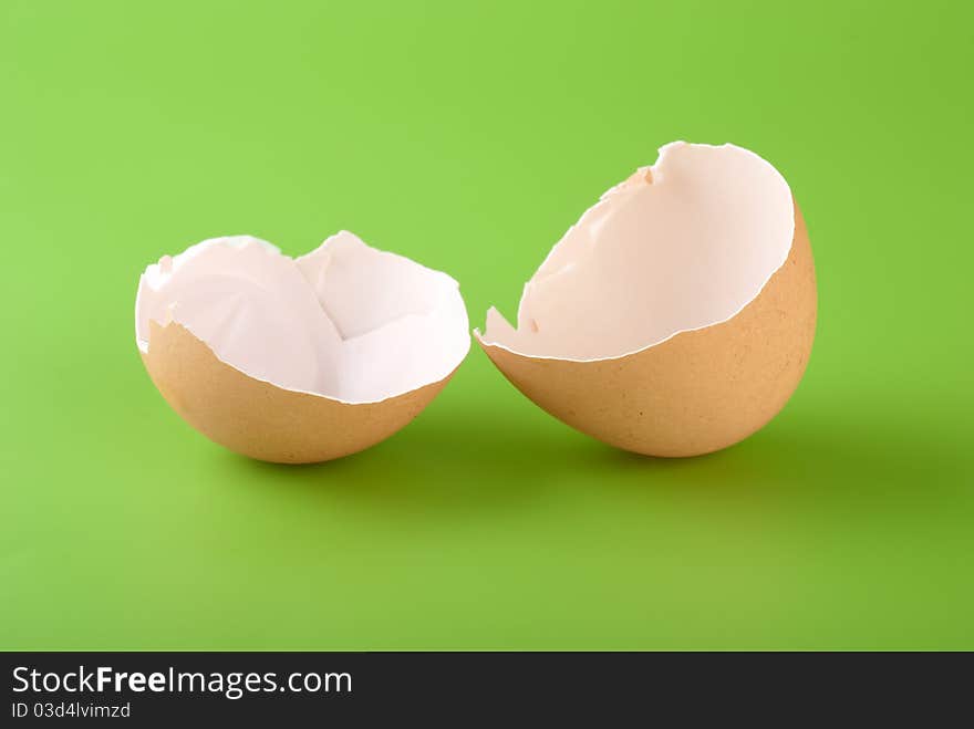 Two pieces of brown egg shell on a green background