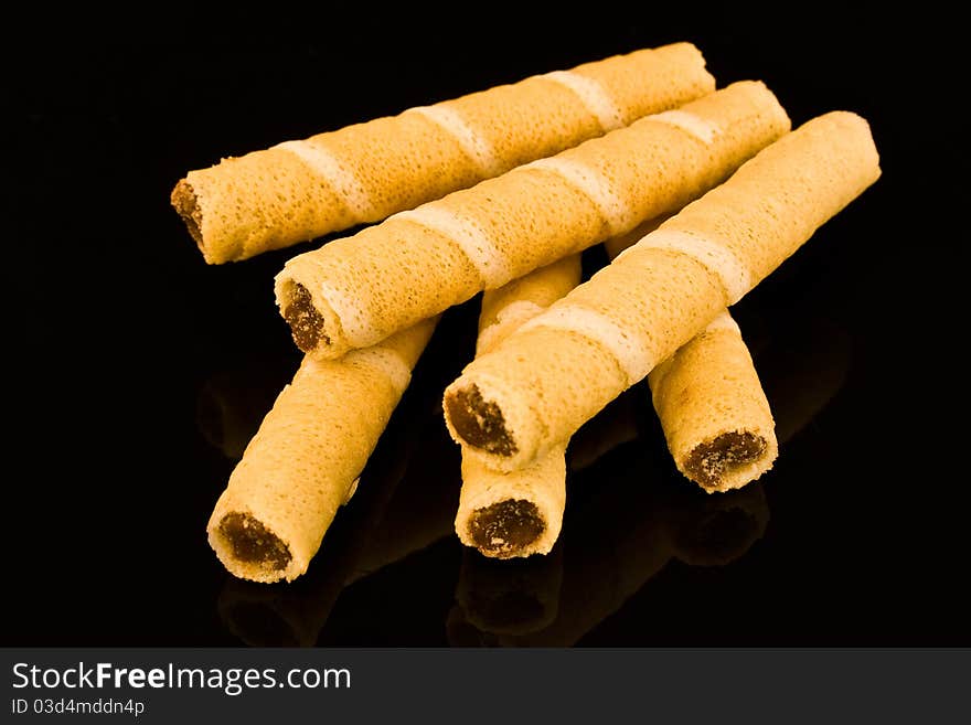 Wafer rolls with chocolate filling on black background