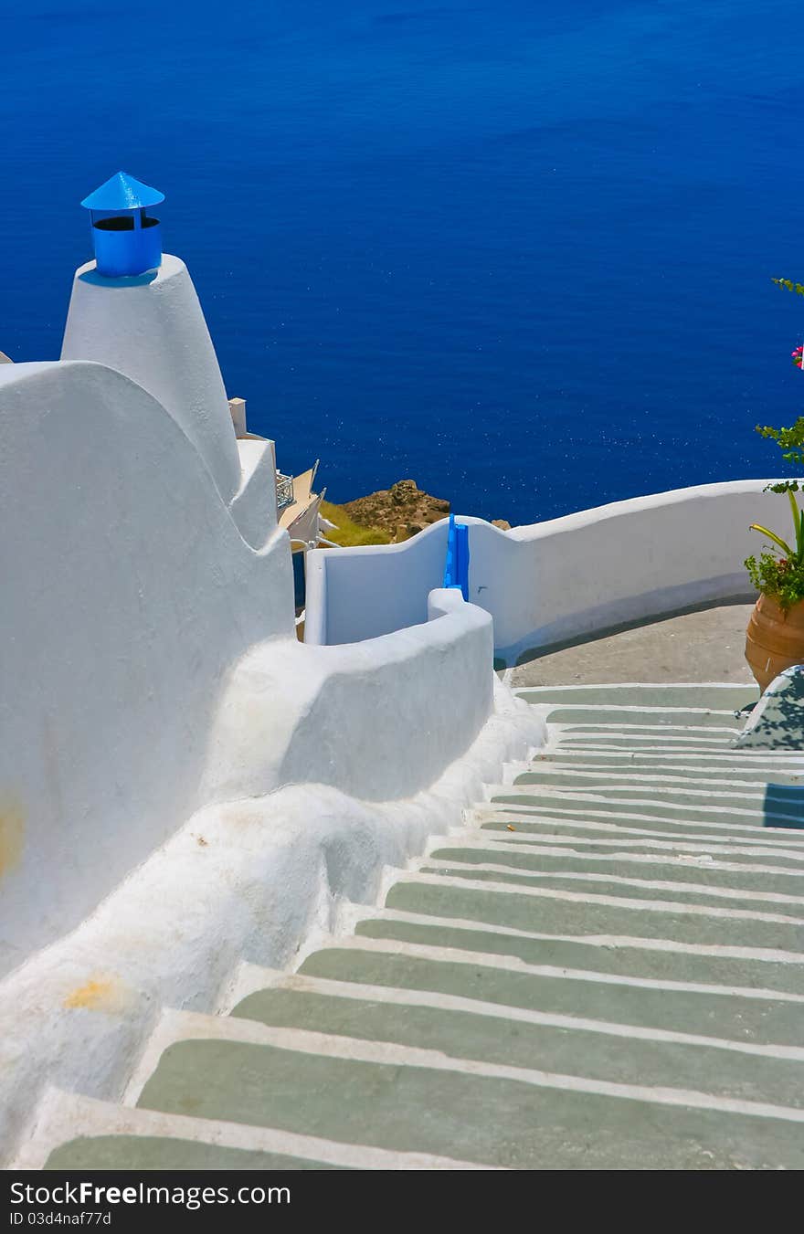 Colorful street with long staircase and traditional architecture on island of Santorini in Fira, Greece. Aegean sea in the background. Colorful street with long staircase and traditional architecture on island of Santorini in Fira, Greece. Aegean sea in the background.