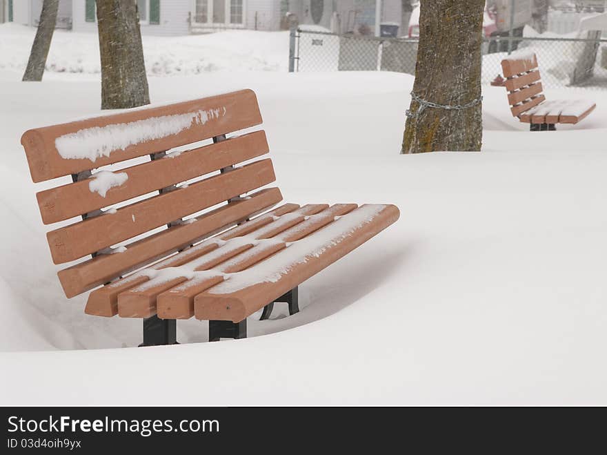 This is two orange bench in a park in a snow storm. This is two orange bench in a park in a snow storm.