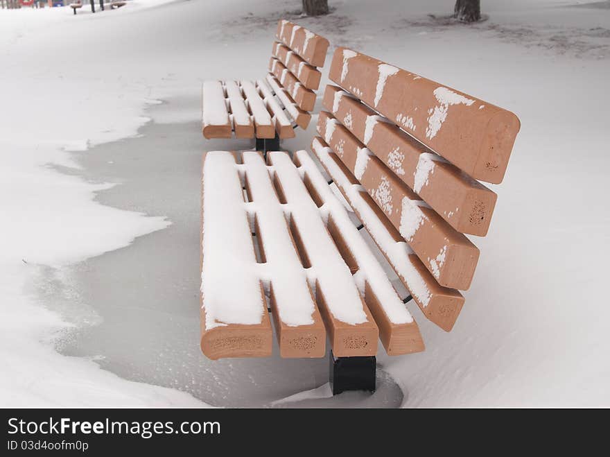 This is two orange bench in a park in a snow storm. This is two orange bench in a park in a snow storm.