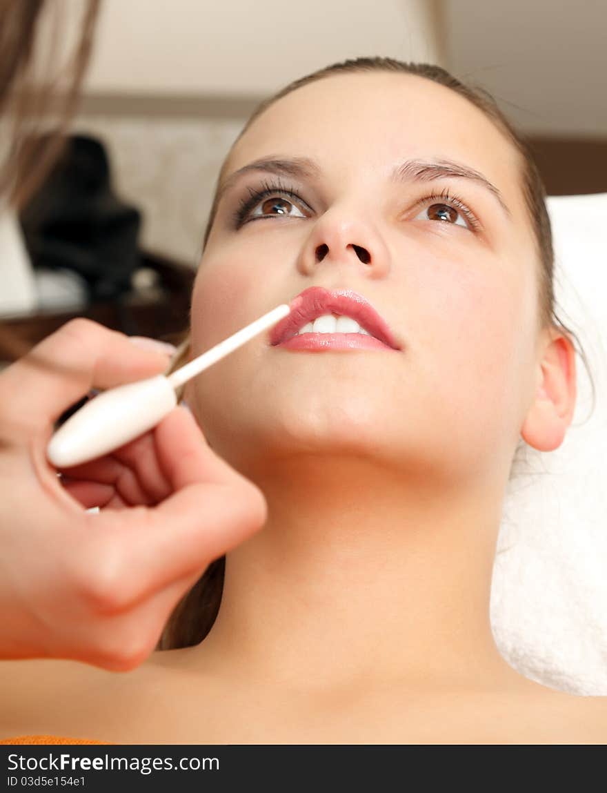 Applying lipstick for a lovely young woman in a salon