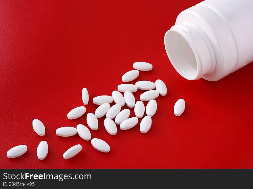 Spread and a bottle of pills lying on a red background. Spread and a bottle of pills lying on a red background