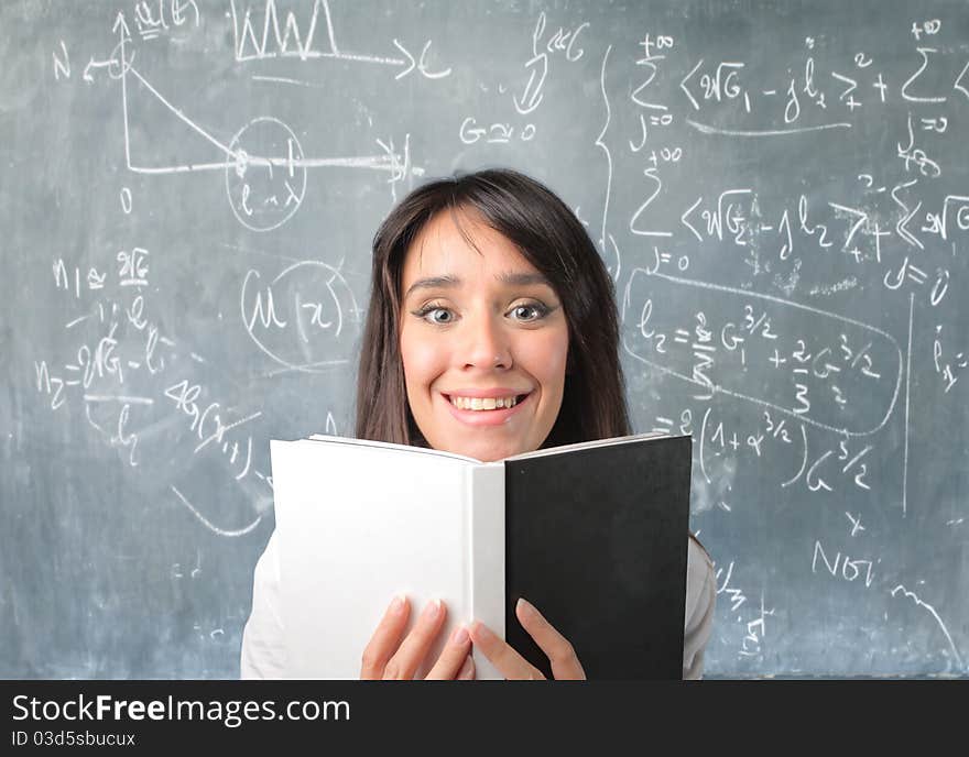 Smiling student reading a book in a classroom