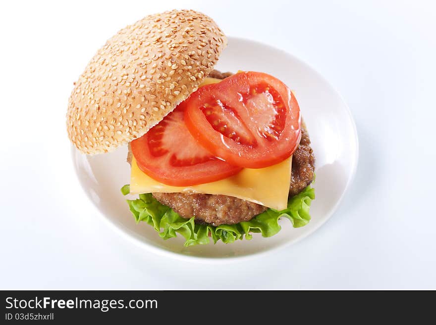 Cheeseburger with tomatoes and lettuce isolated on white