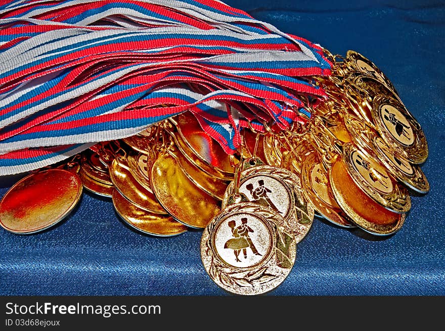 Many gold dance medals with ribbons on blue background. Many gold dance medals with ribbons on blue background