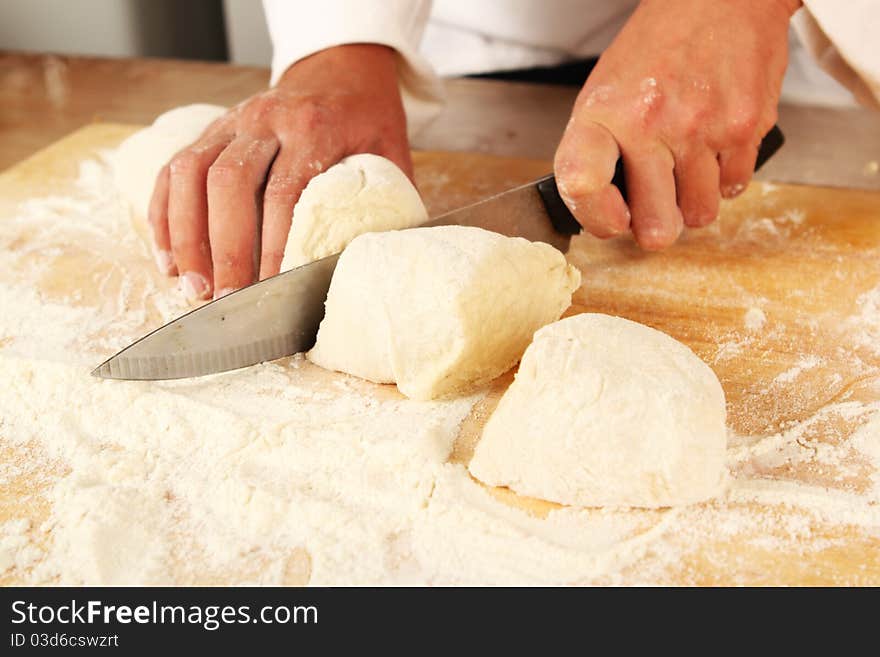 Chef cutting dough into segments on a chopping board