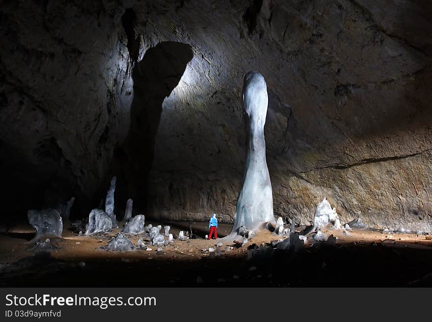 The cave explorer being in a cave with large ice stalactites. The cave explorer being in a cave with large ice stalactites.