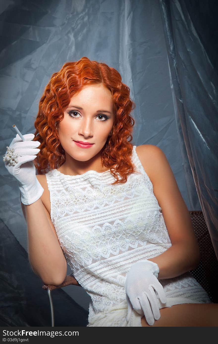 girl with beautiful red curly hair wearing white short dress and gloves holding cigarette. girl with beautiful red curly hair wearing white short dress and gloves holding cigarette