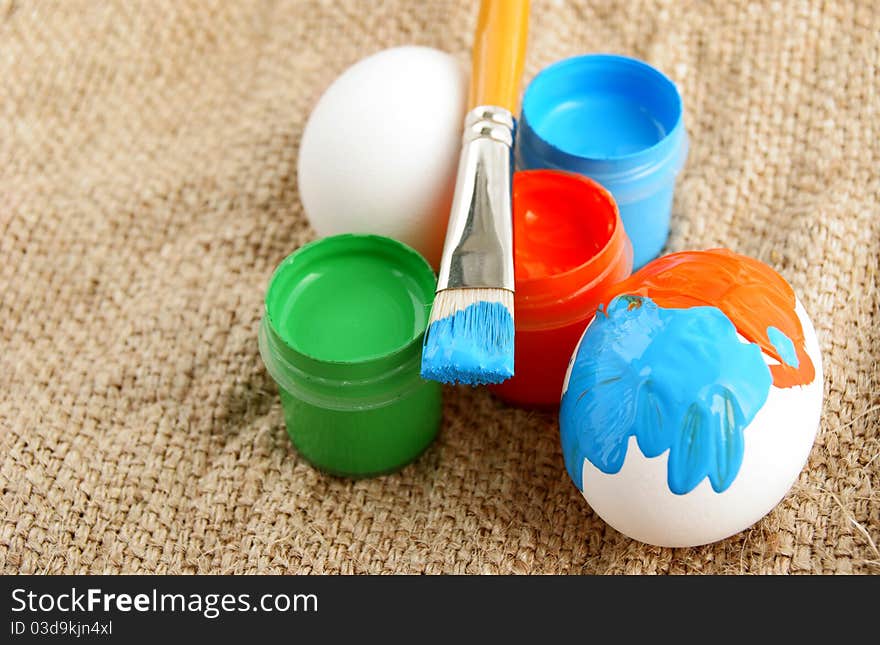 Easter eggs brush and Jars with a bright paint on a rough canvas background