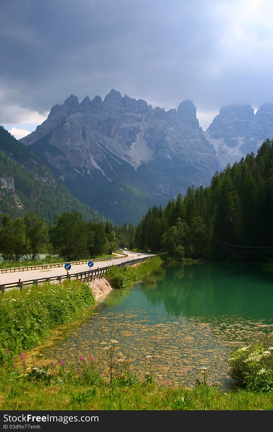 Amazing high mountains on the road in Italian alps. Beautiful nature with a clear lake and green forest. Amazing high mountains on the road in Italian alps. Beautiful nature with a clear lake and green forest.