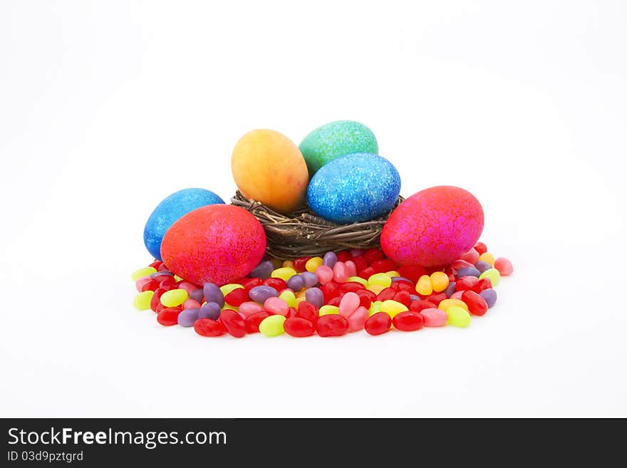 Mottle colored Easter eggs in a natural twig nest sit on colorful jelly beans. Mottle colored Easter eggs in a natural twig nest sit on colorful jelly beans