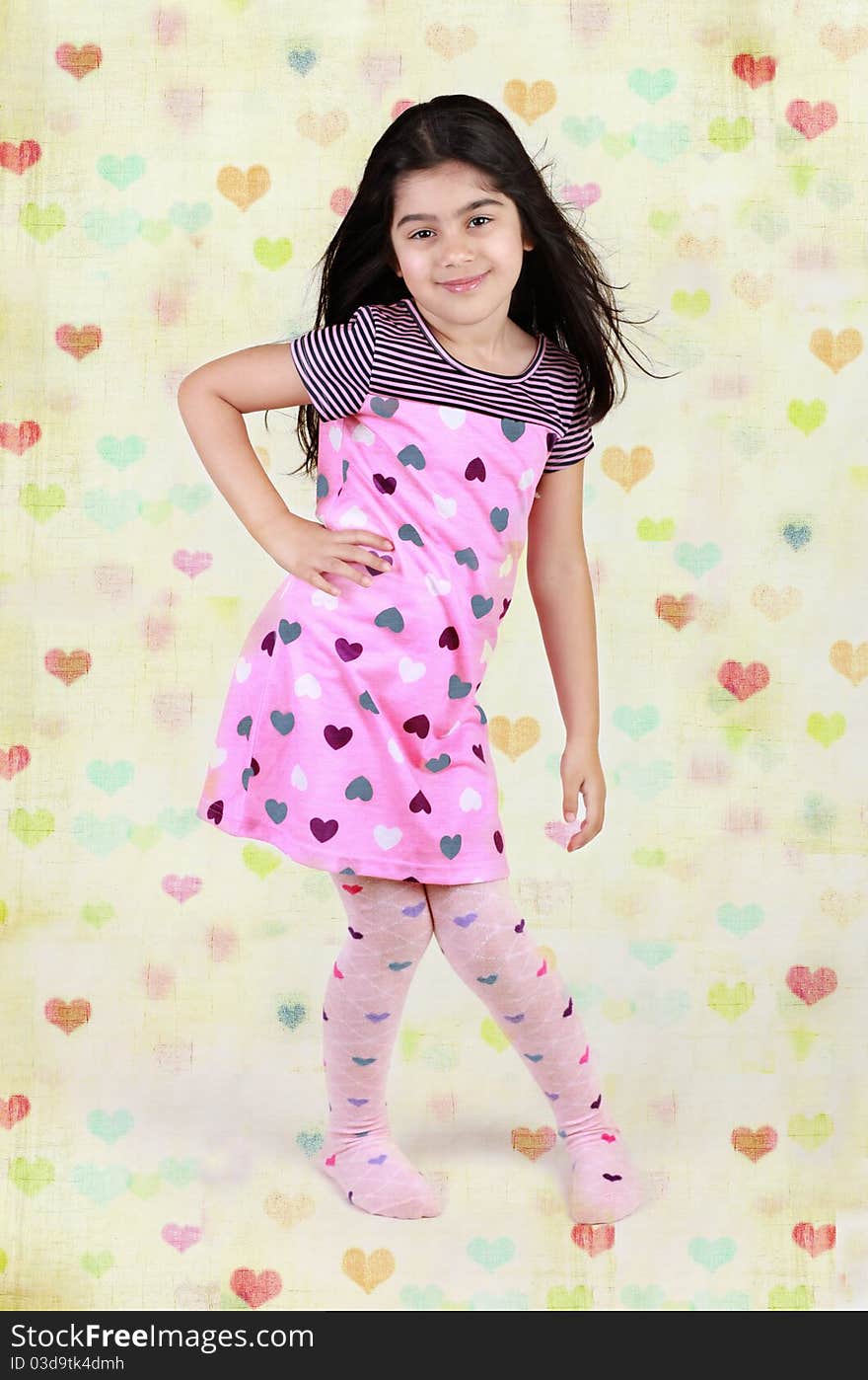 Little girl dressed in heart shaped dress and leggings with hears background. Little girl dressed in heart shaped dress and leggings with hears background.