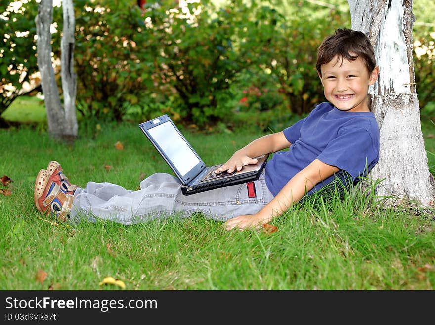 Boy with notebook sit at tree outdoors