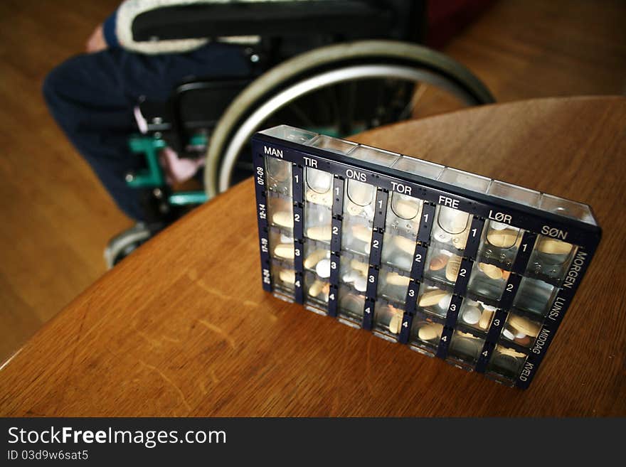 Pill board with wheelchair in the background.