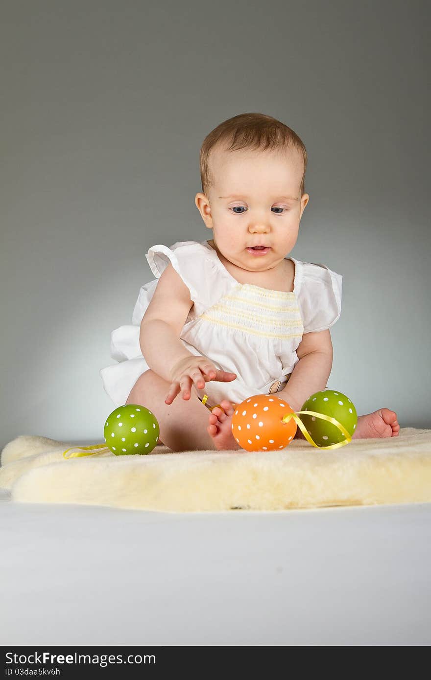 Young babay girl sitting and playing with easter egg. Very cute baby. Young babay girl sitting and playing with easter egg. Very cute baby.