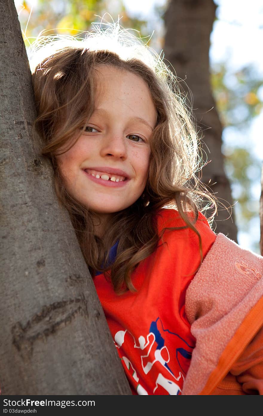 Pretty young girl climbing tree and smiling. Pretty young girl climbing tree and smiling