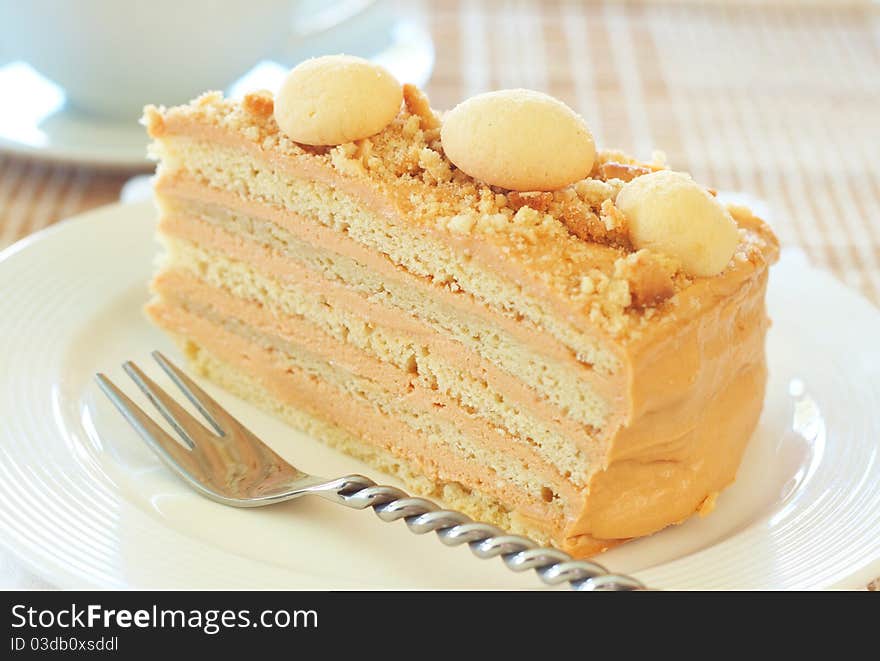 Caramel medovik cake made of honey and caramel cream, decorated with shortbread cookies on white plate